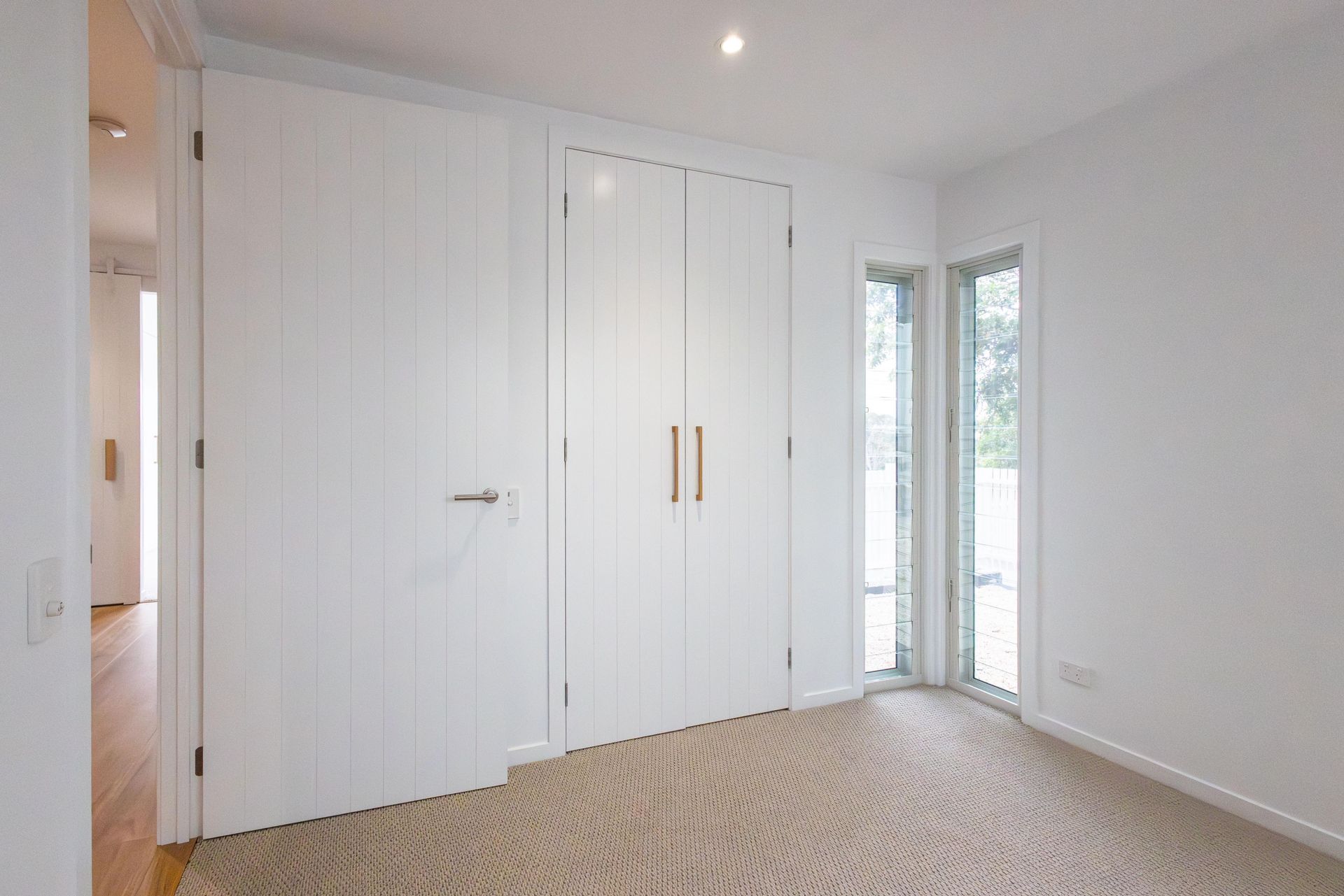 An empty bedroom with white walls and a carpeted floor.