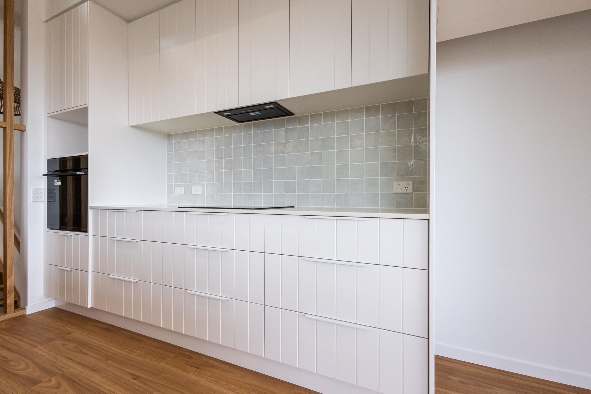 A kitchen with white cabinets and a wooden floor.