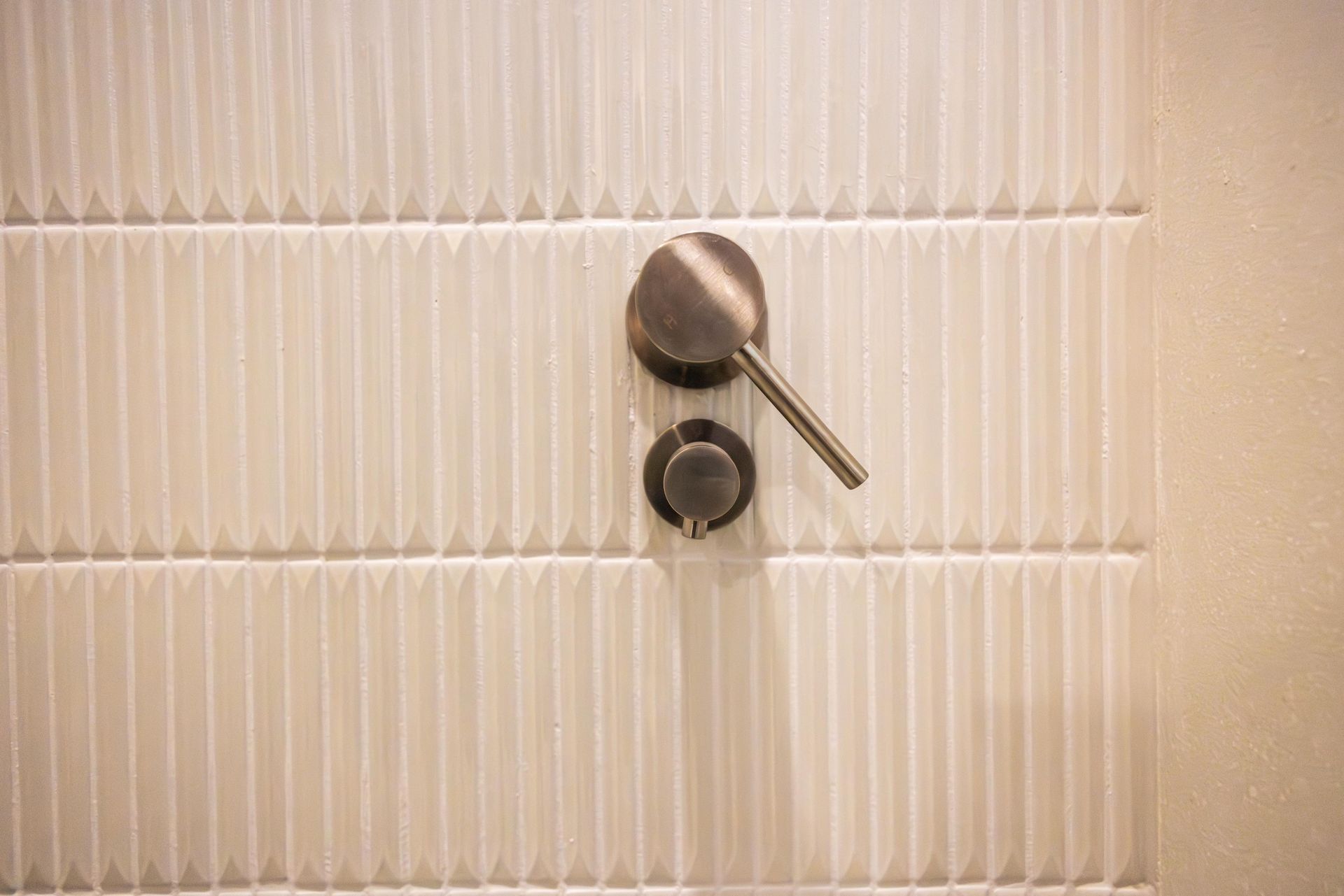 A close up of a shower head on a tiled wall.