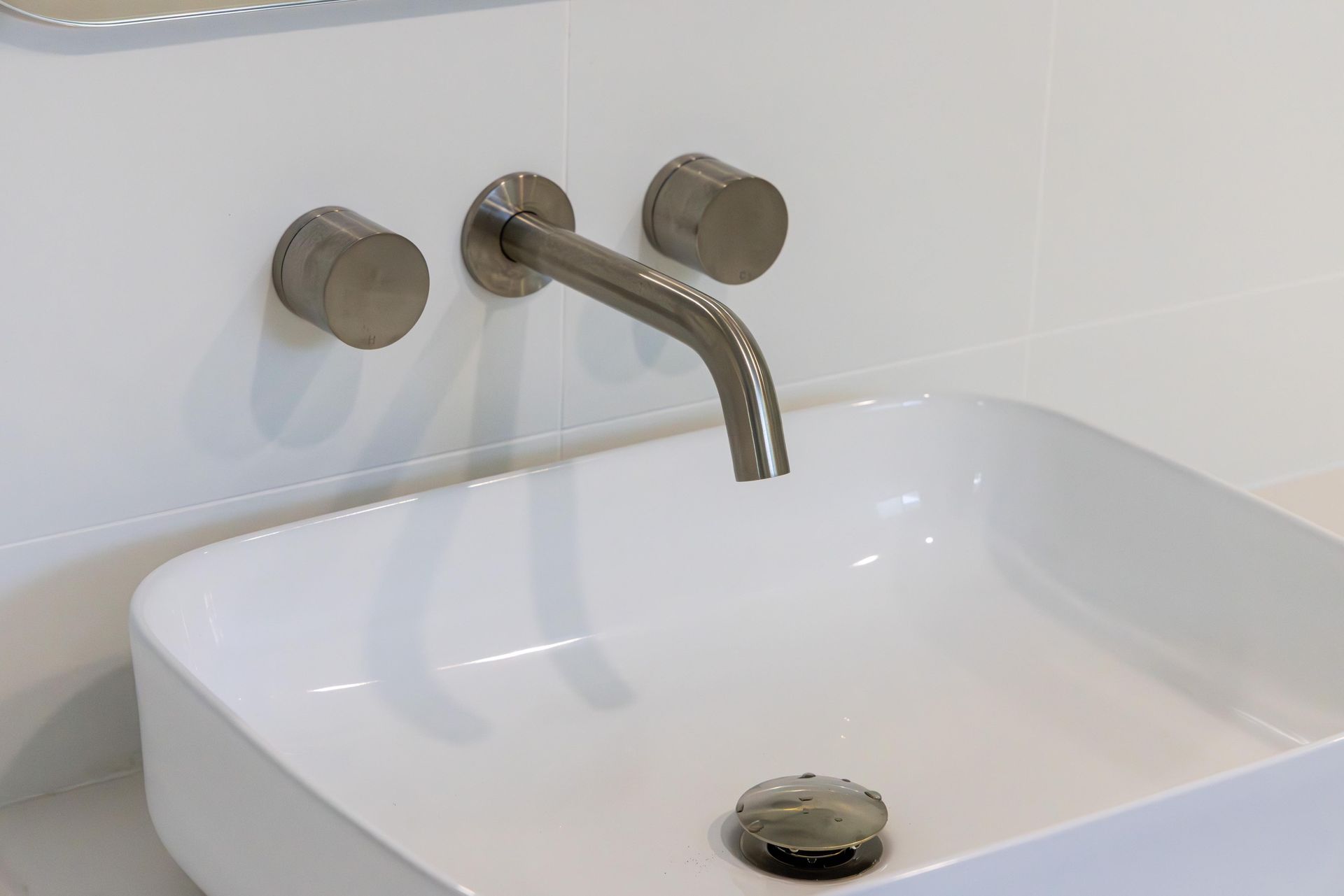 A bathroom sink with a faucet on the wall above it