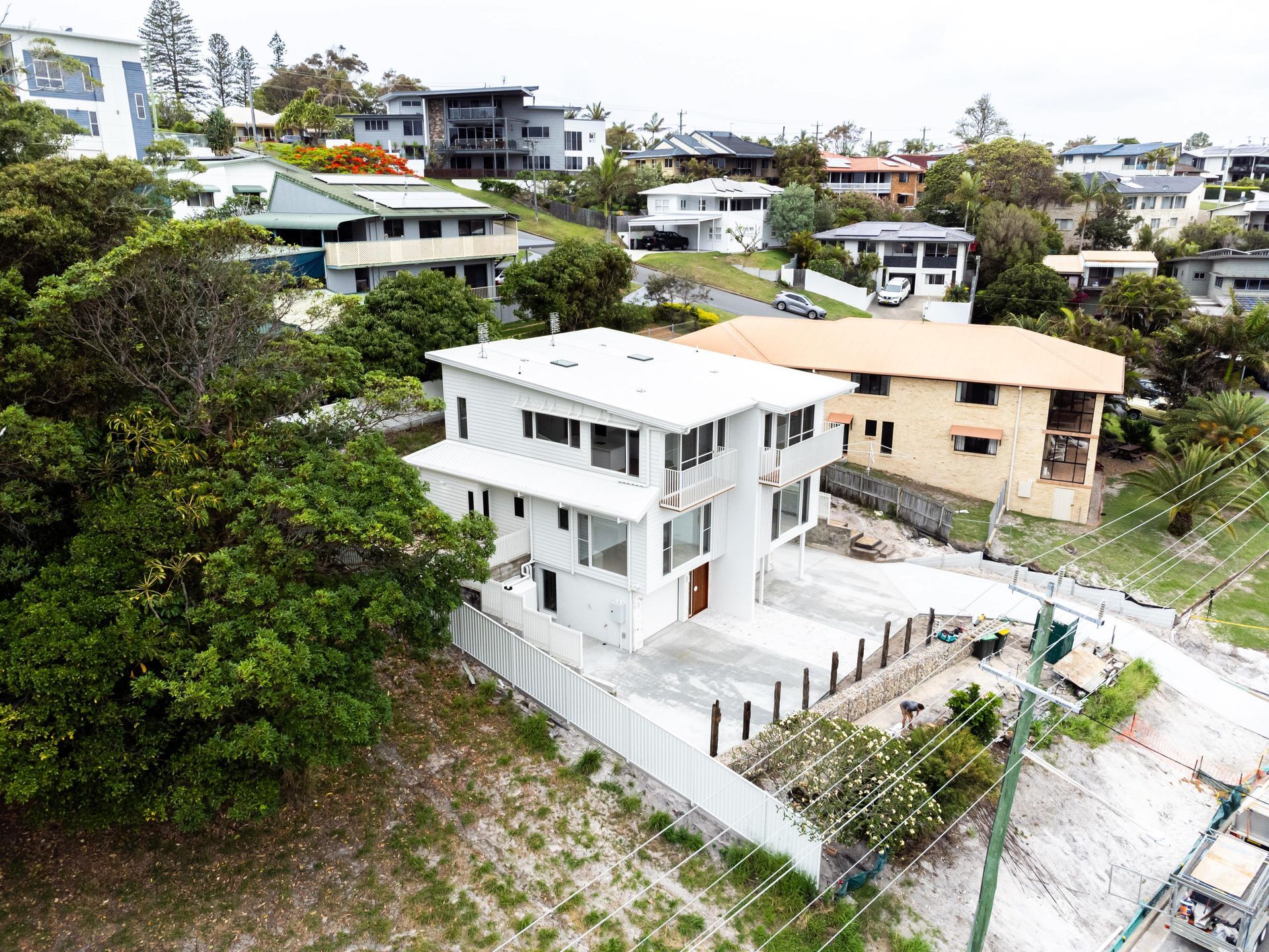 An aerial view of a house on a hill in a residential area surrounded by trees.