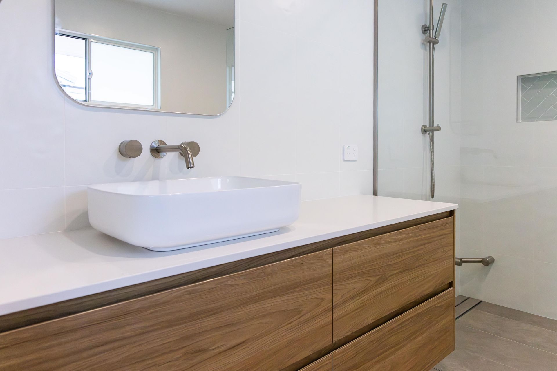 A bathroom with a sink , mirror and shower.