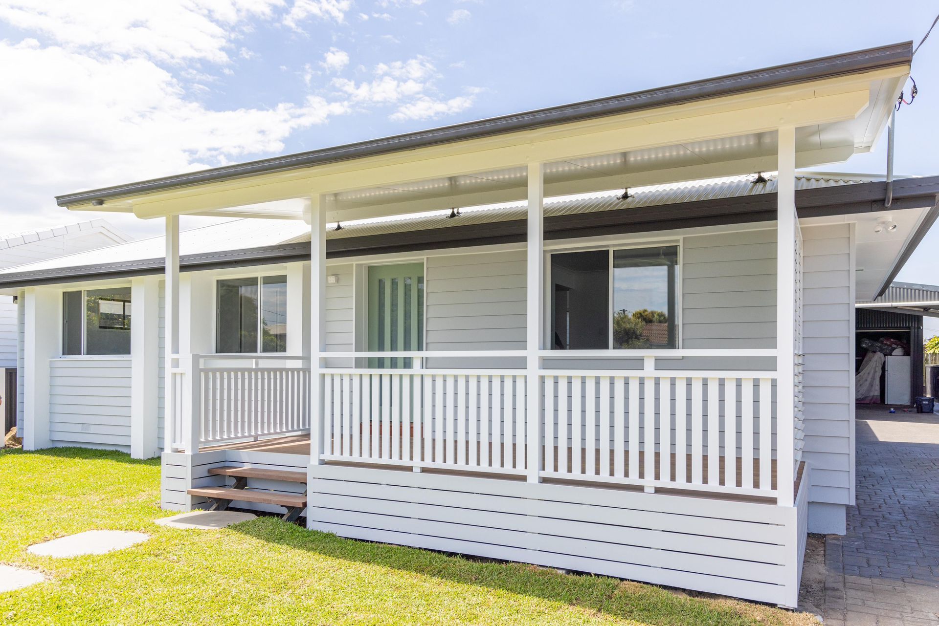 A white house with a porch and a large window.