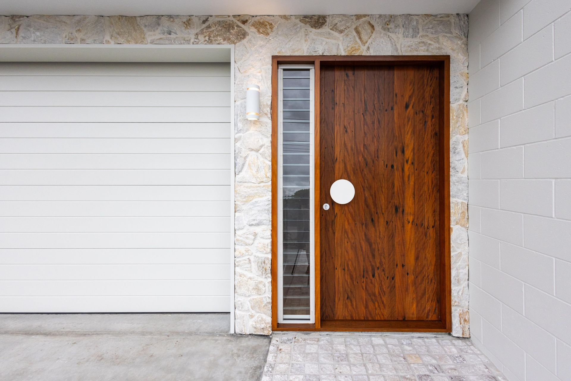 A wooden door is sitting next to a white garage door.