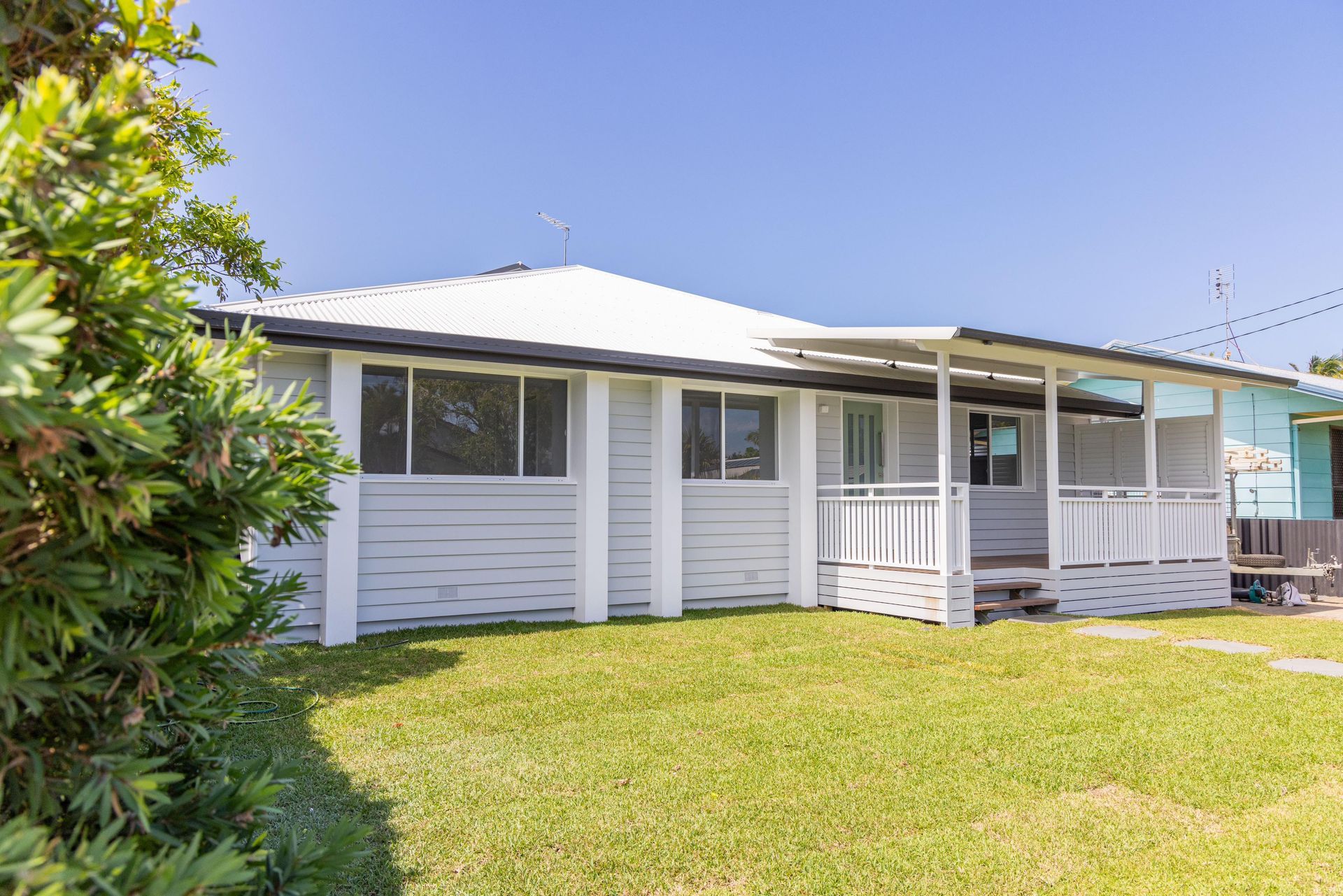 A white house with a porch and a large lawn in front of it.