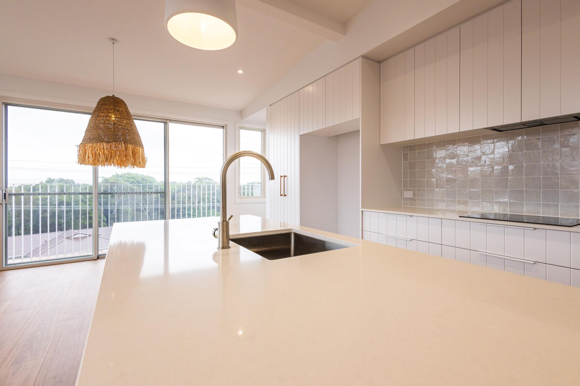 An empty kitchen with white cabinets and a sink.