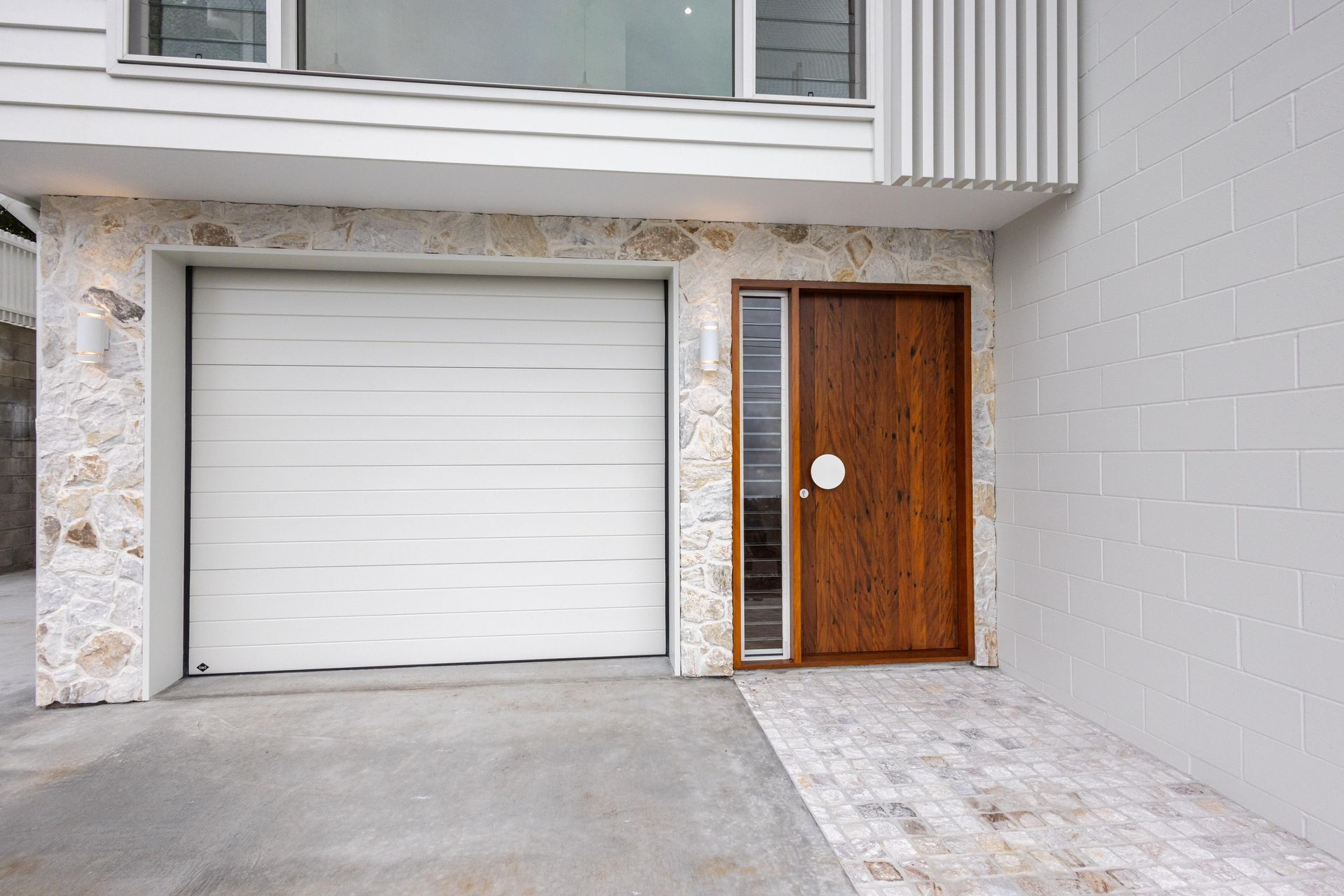 A white garage door is next to a wooden door.