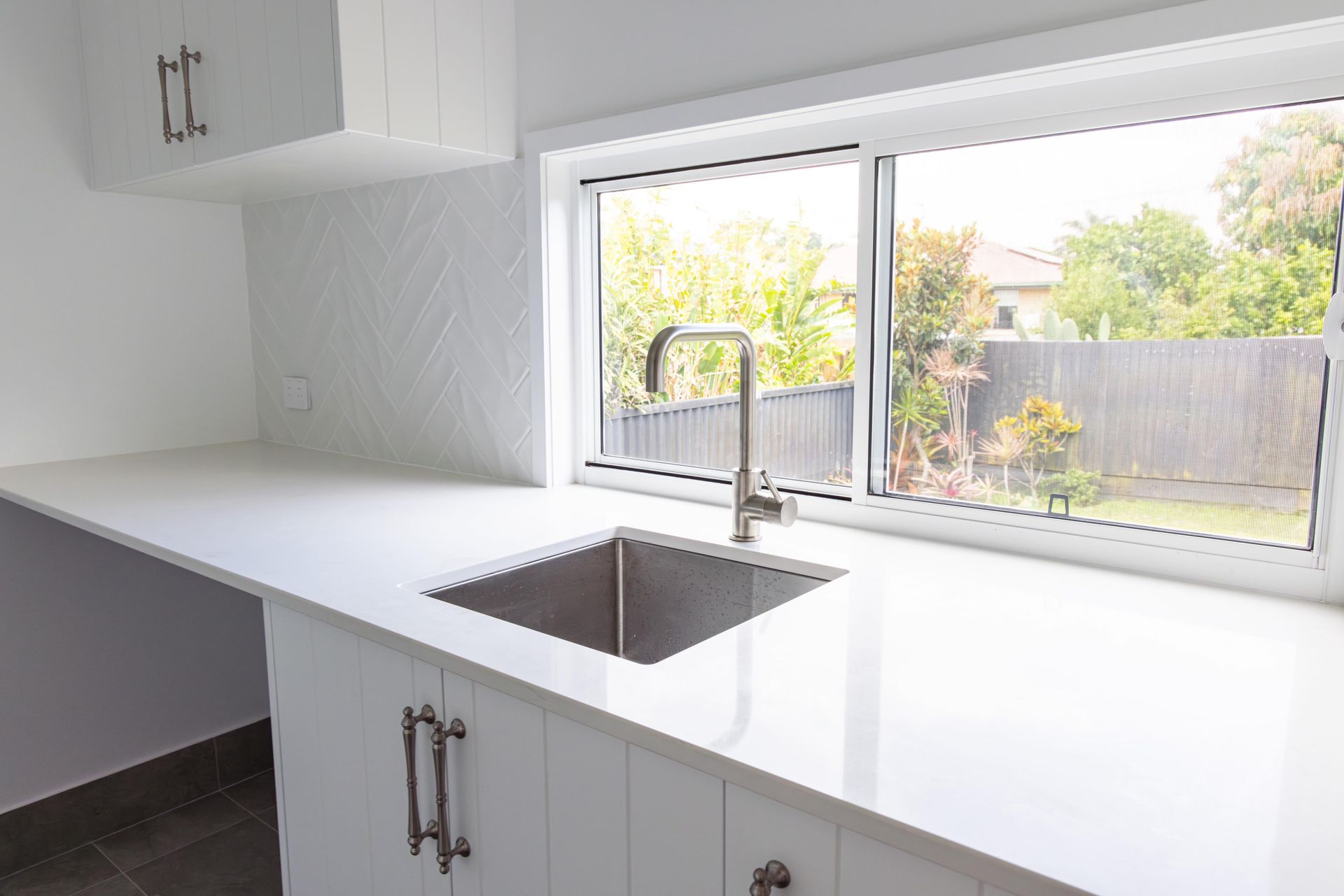 An empty kitchen with a sink and a window.