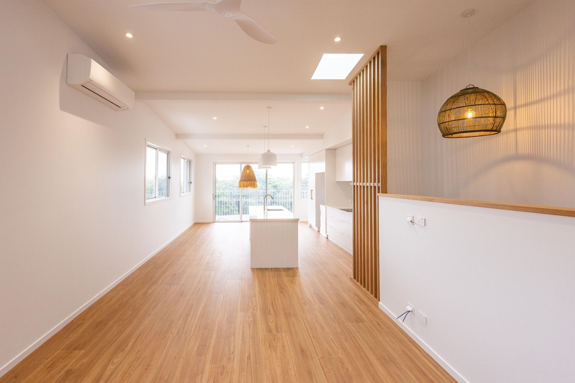 An empty living room with hardwood floors and white walls.
