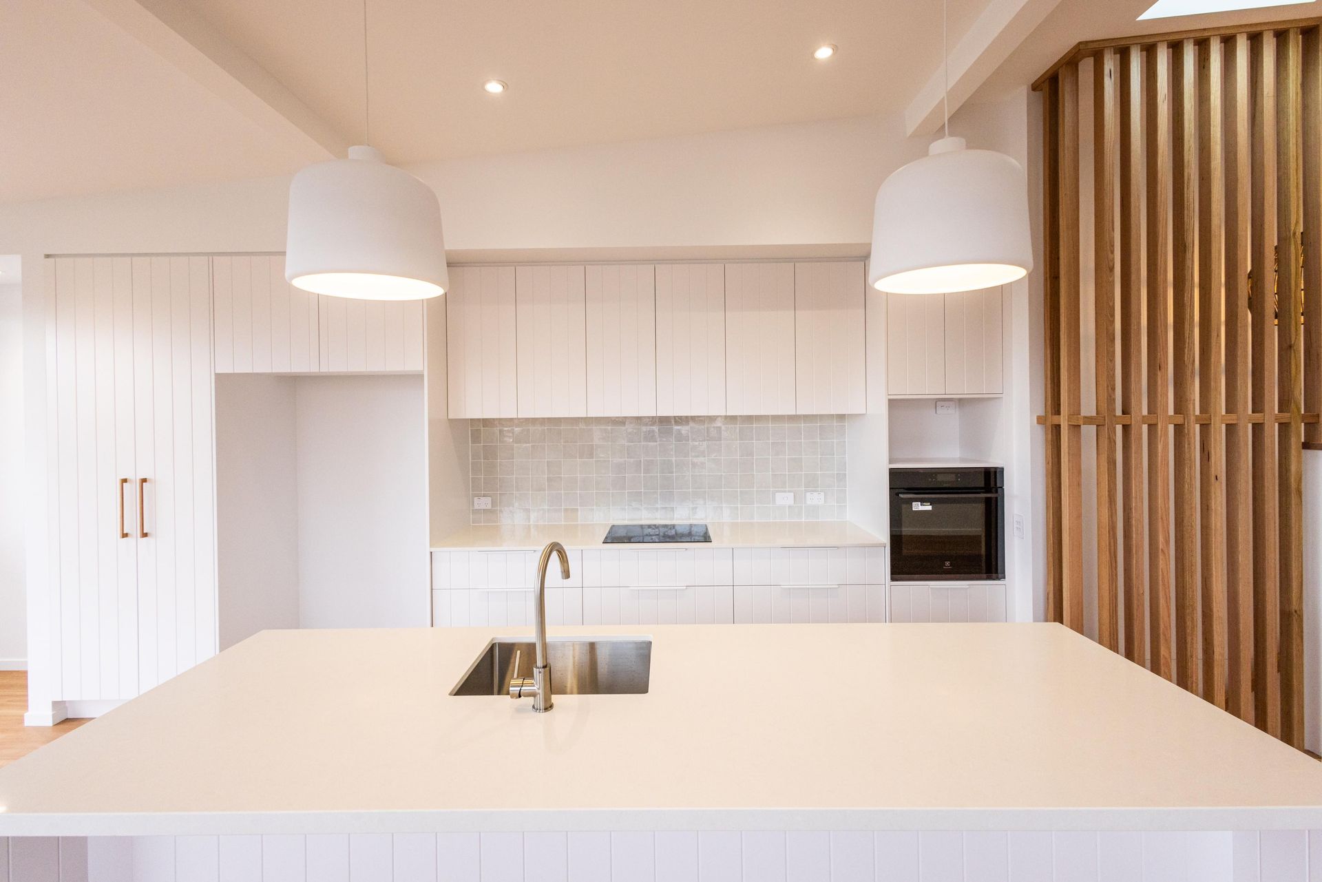 A kitchen with white cabinets , a sink , and a wooden divider.