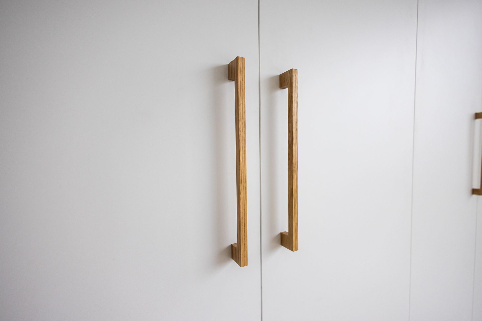 A close up of a white cabinet with wooden handles.