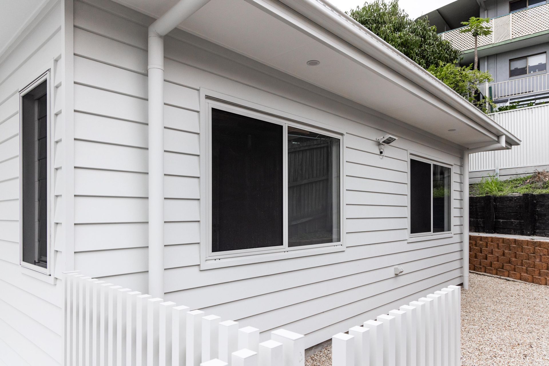 A white house with black windows and a white fence