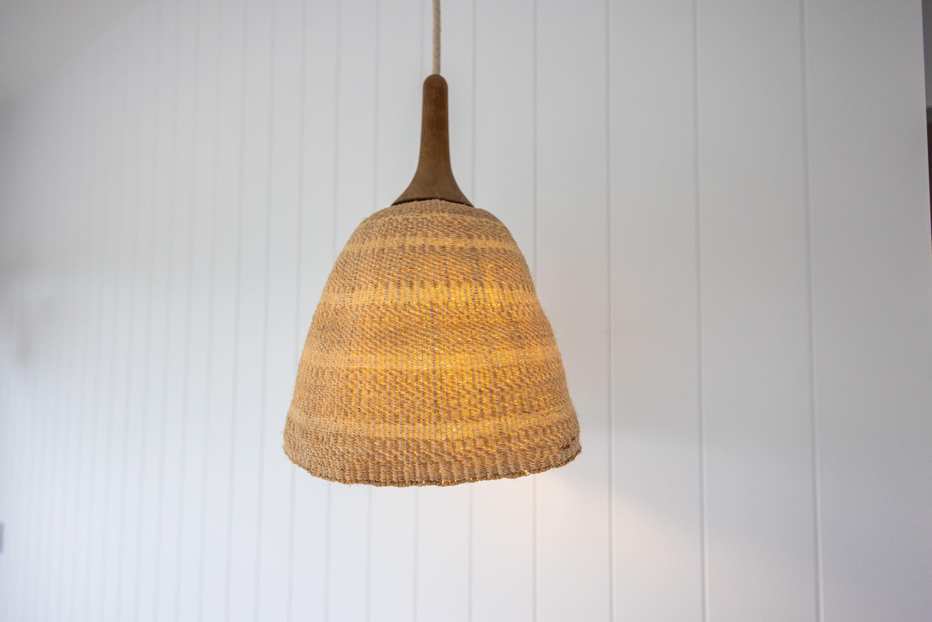 A lamp with a wicker shade is hanging from the ceiling