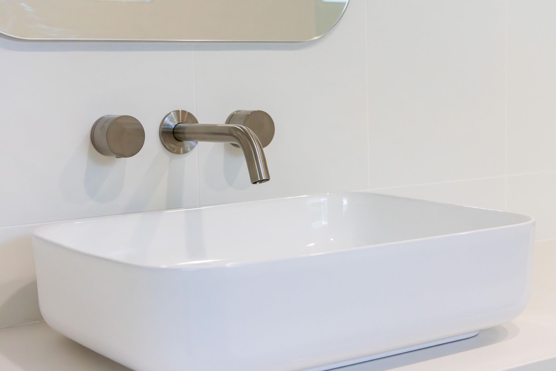 A white sink is sitting on a counter in a bathroom next to a mirror.