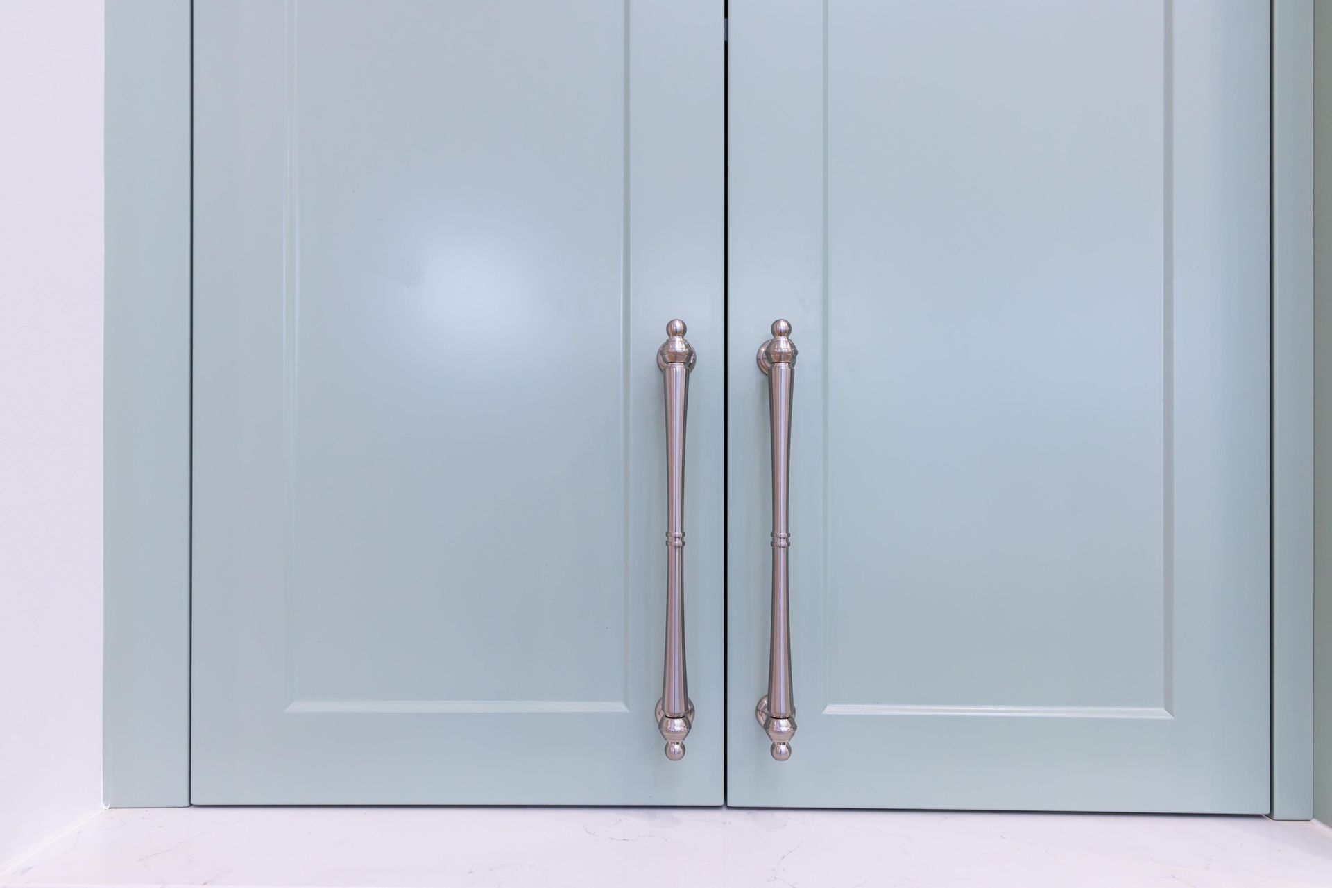 A close up of a light blue cabinet with stainless steel handles.