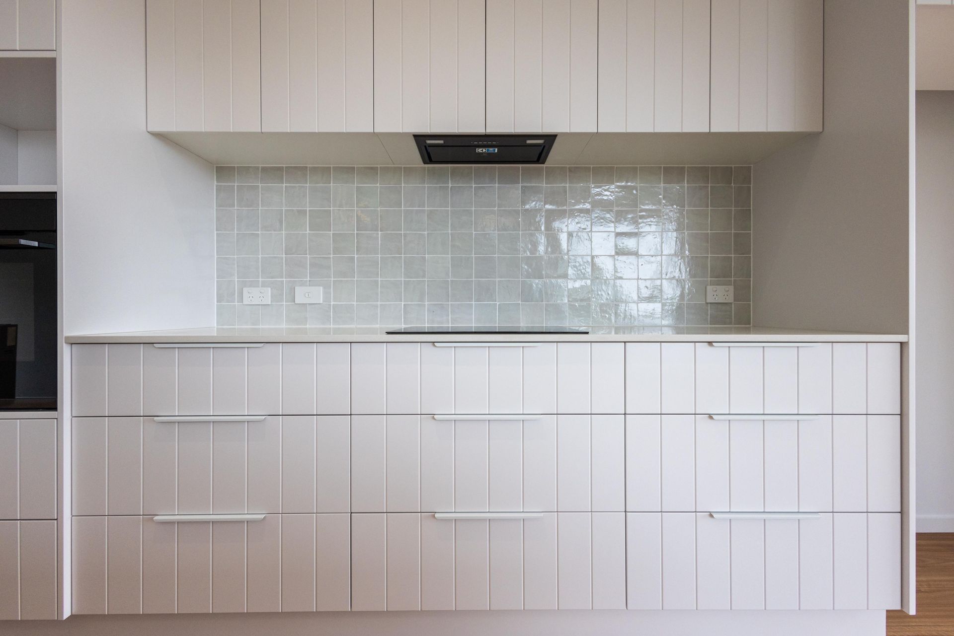 A kitchen with white cabinets , white counter tops , and a stove top oven.