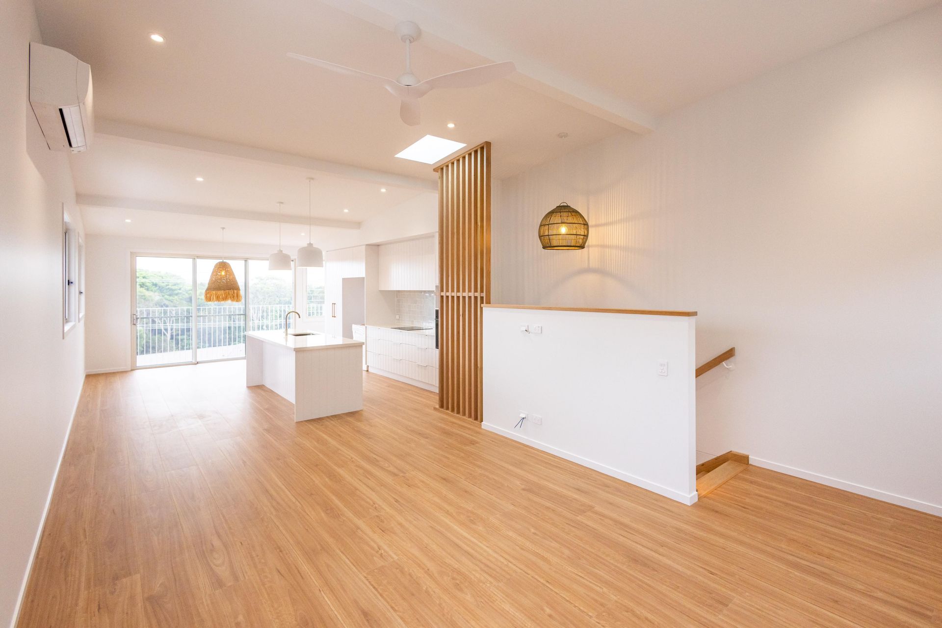 A large empty room with hardwood floors and white walls.