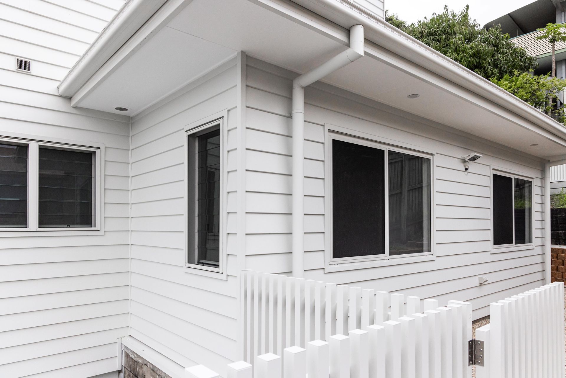 A white house with a white picket fence in front of it.