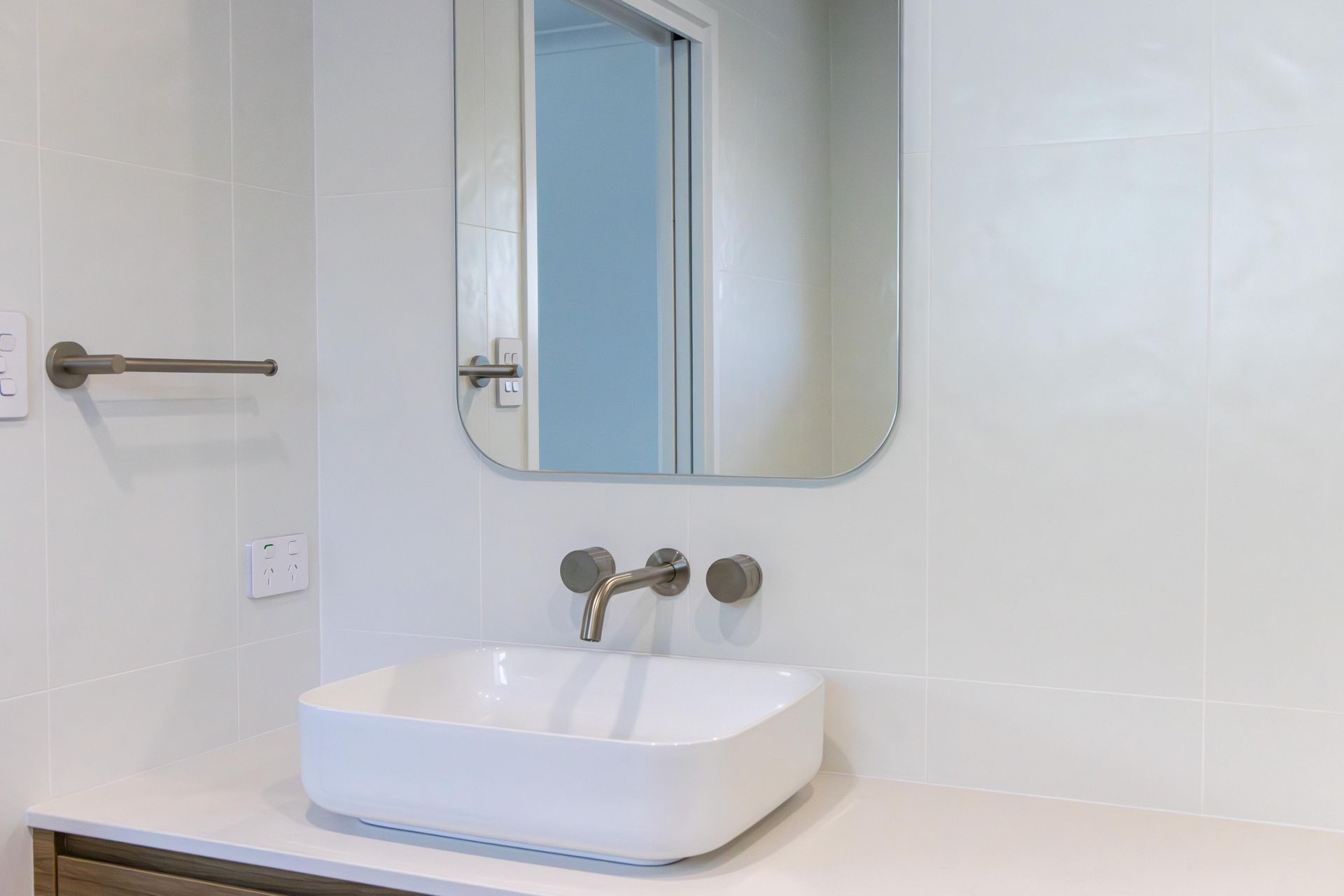 A bathroom with a sink , mirror and towel rack.