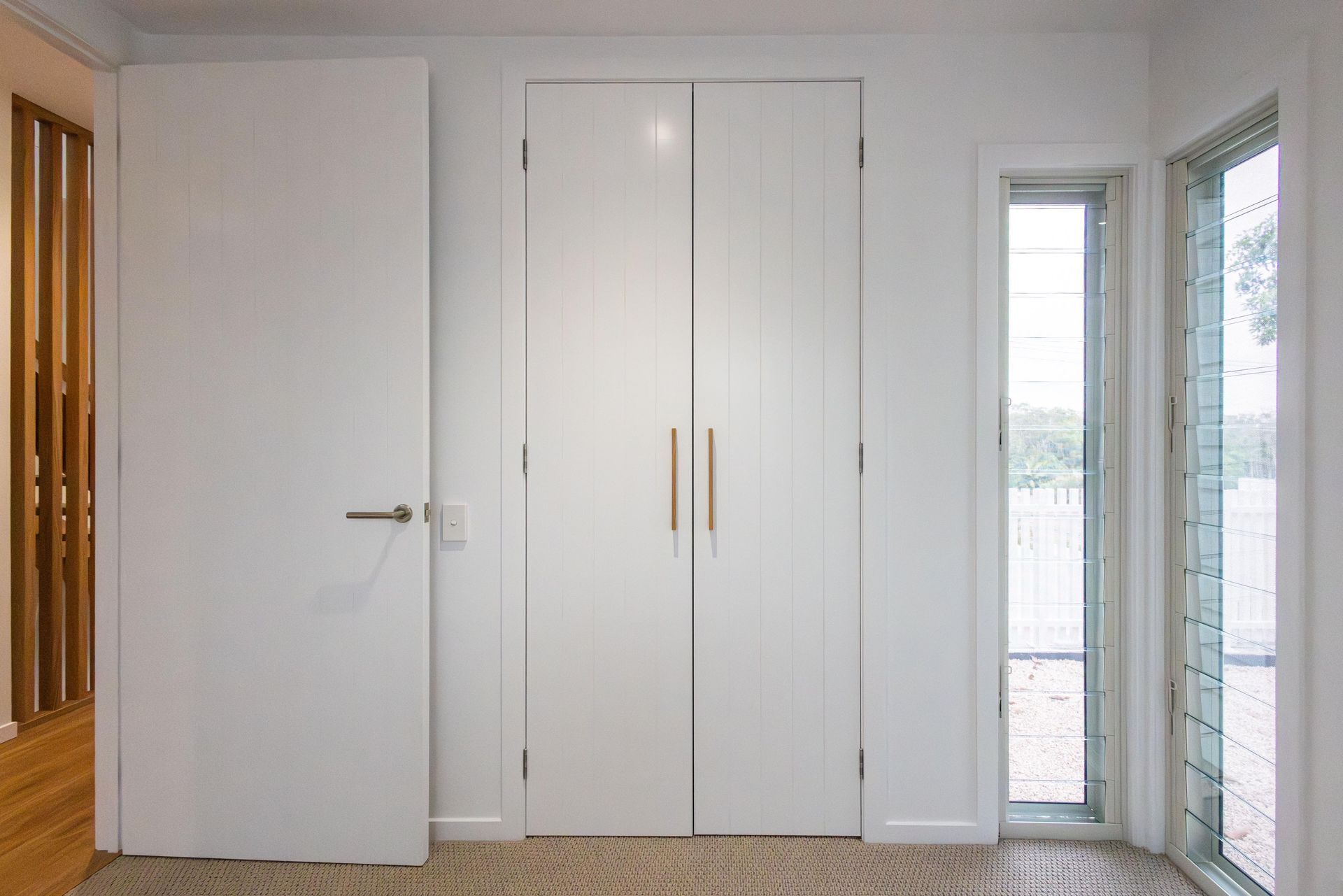 A room with two white doors and a window.