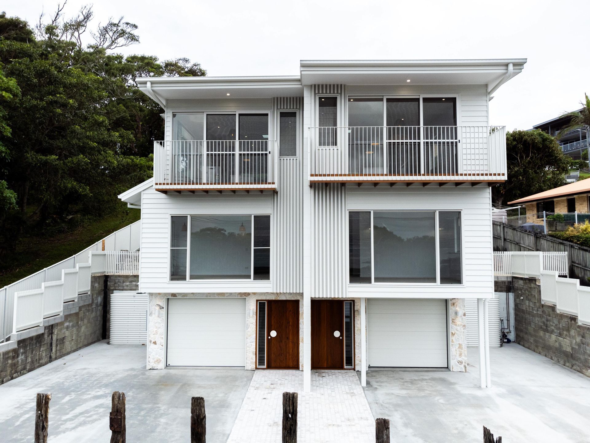 A white house with two garages and a balcony