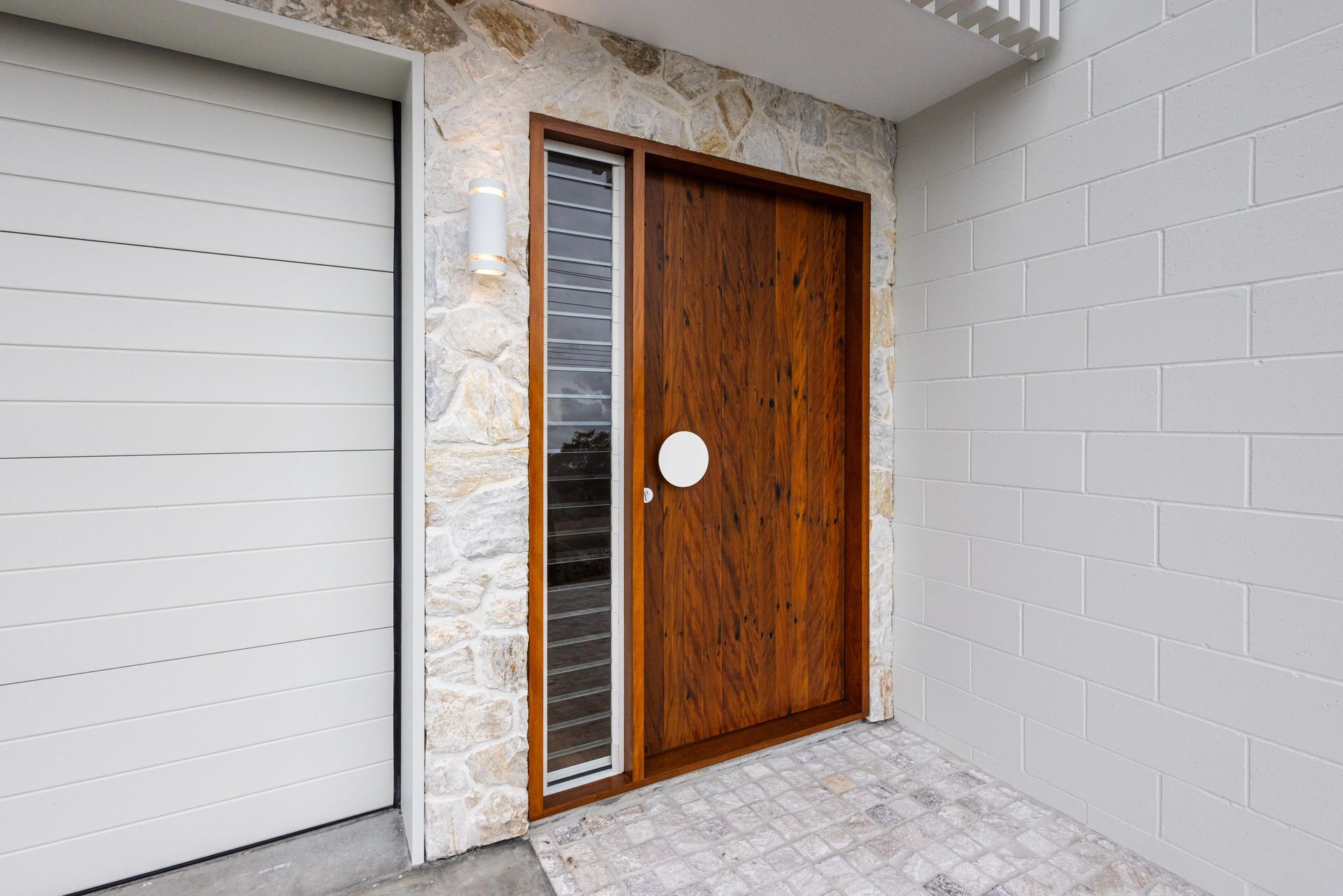 A wooden door is sitting next to a white garage door.