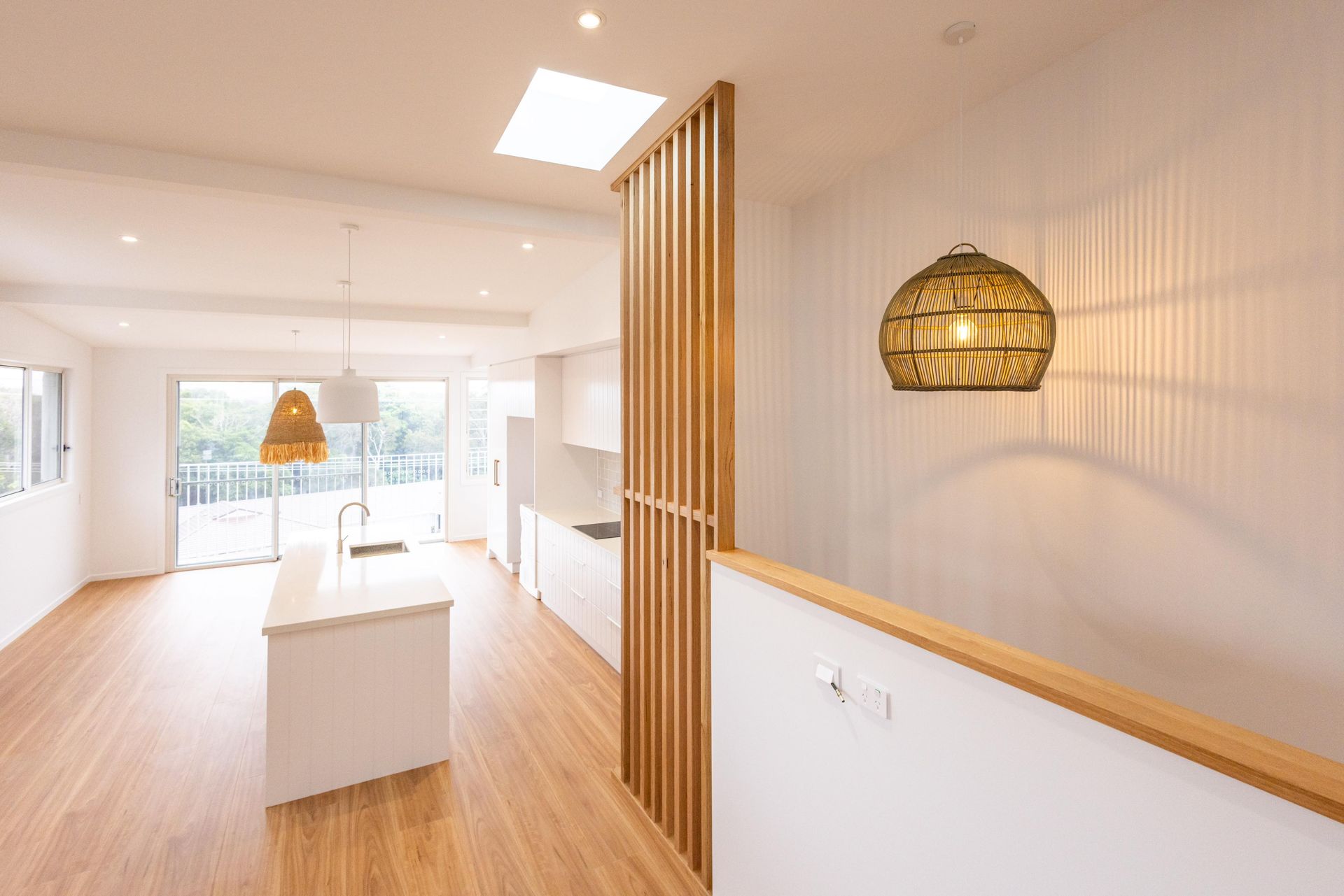 A kitchen with a wooden divider between the kitchen and the living room.