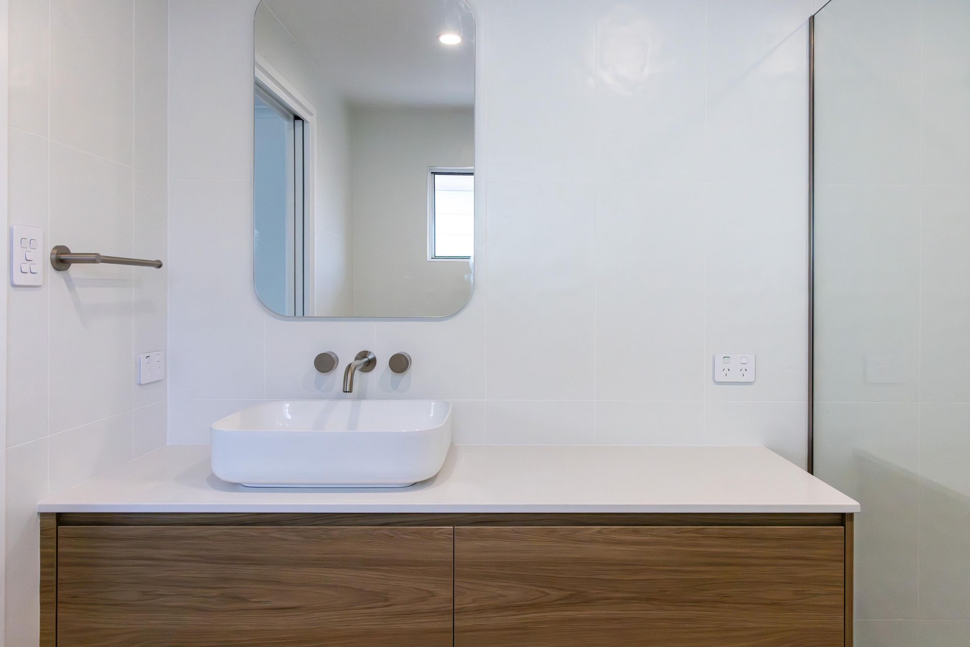 A bathroom with a sink , mirror and walk in shower.