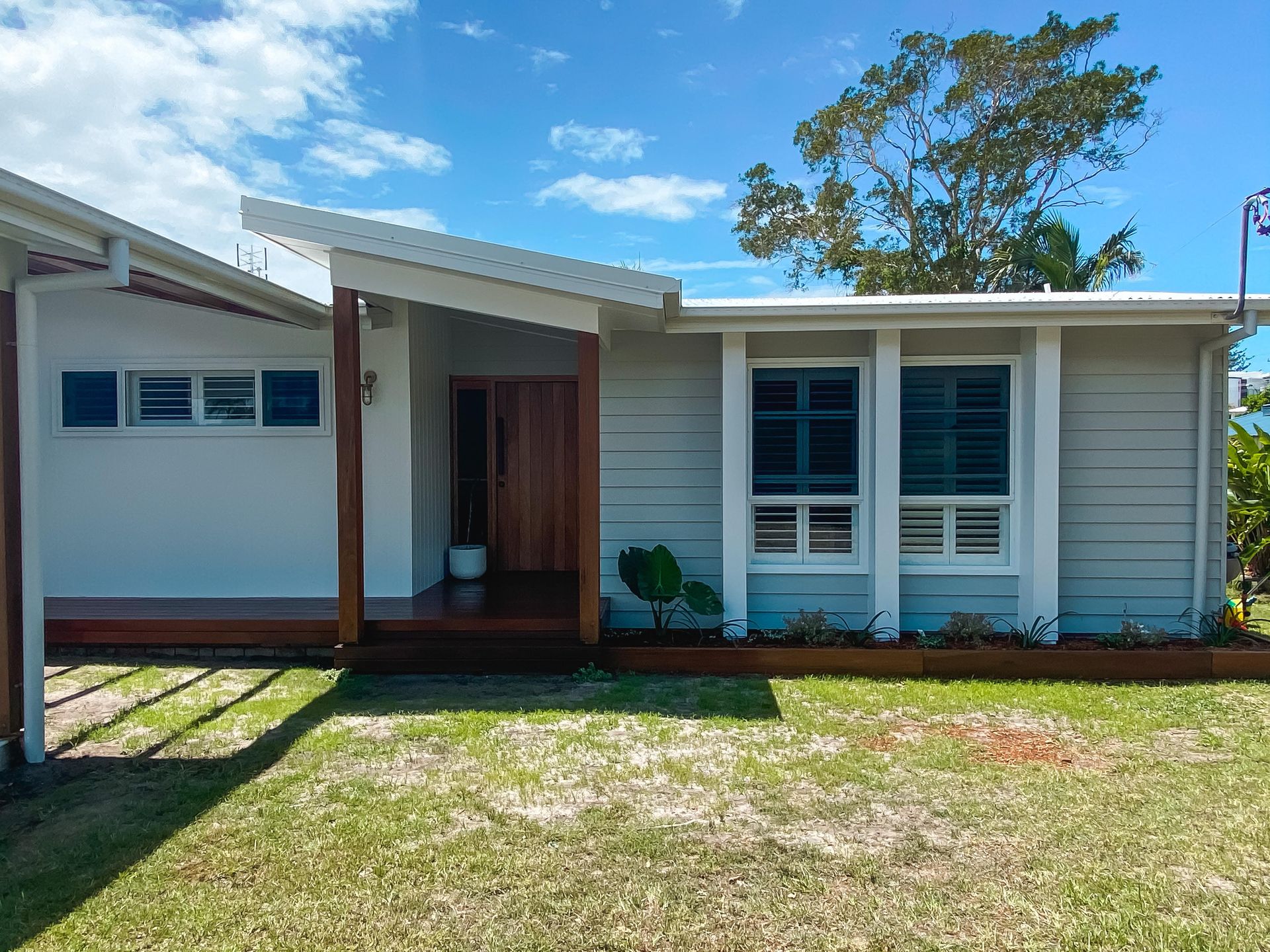 A white house with a porch and a blue sky in the background