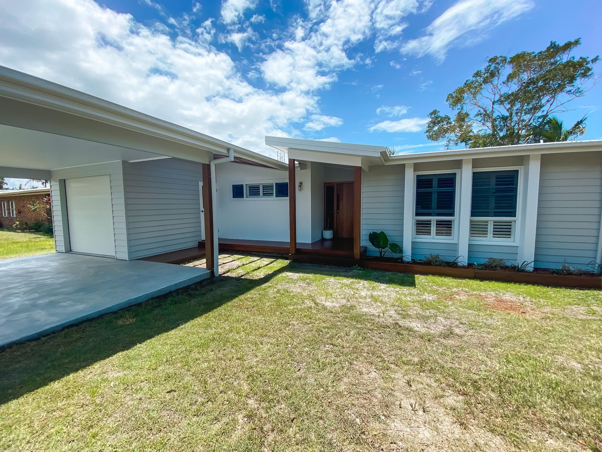 A house with a carport and a porch on a sunny day.