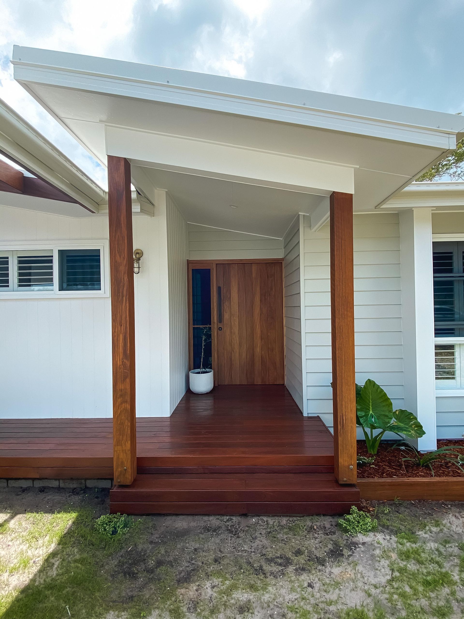 A white house with a wooden porch and a wooden door.