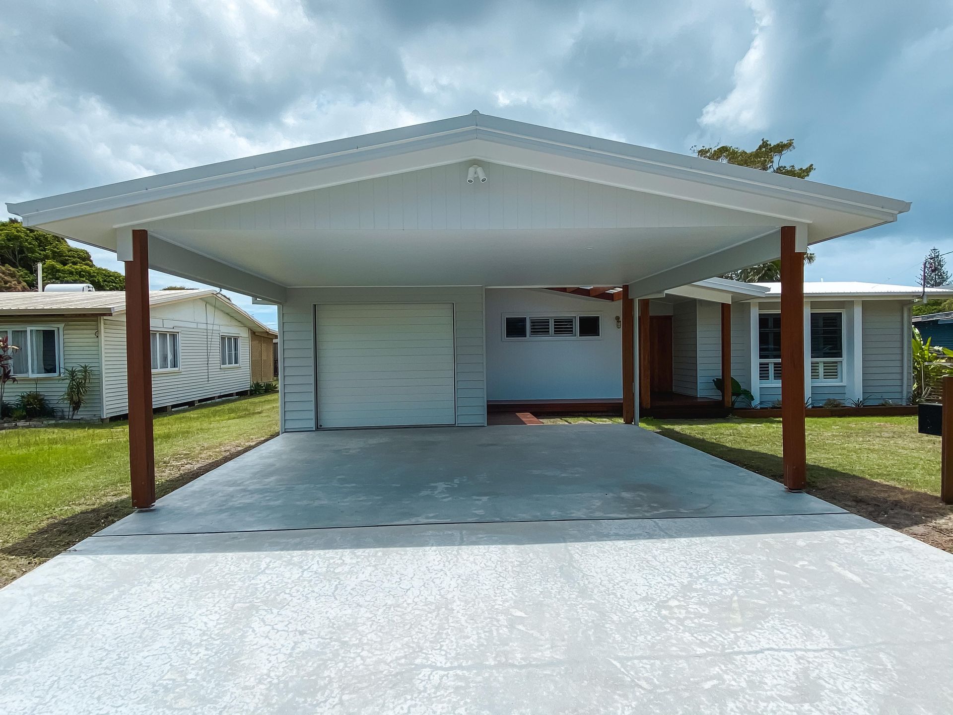 A white house with a carport in front of it.
