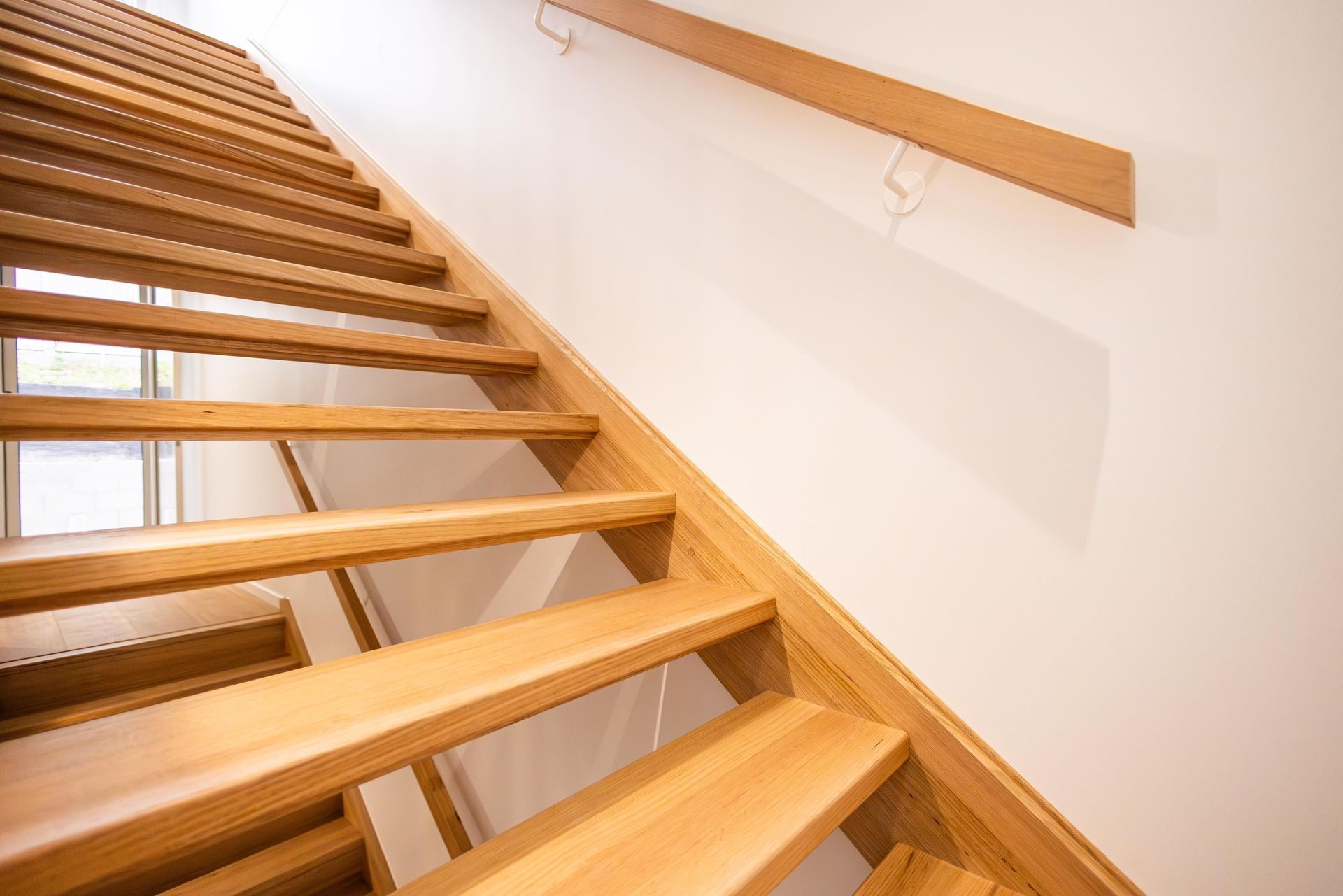 A wooden staircase with a white wall behind it