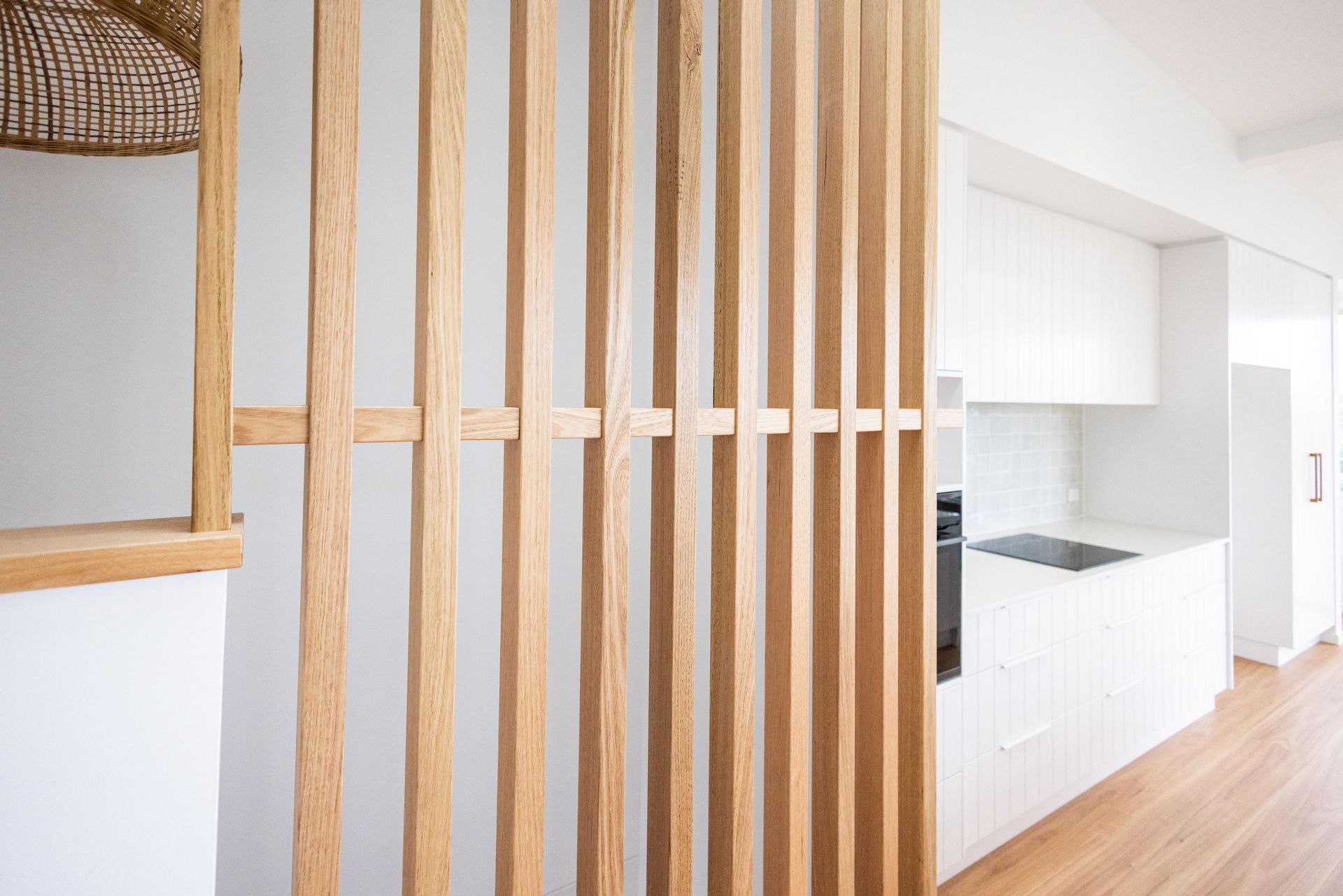 A kitchen with a wooden divider between the kitchen and the living room.