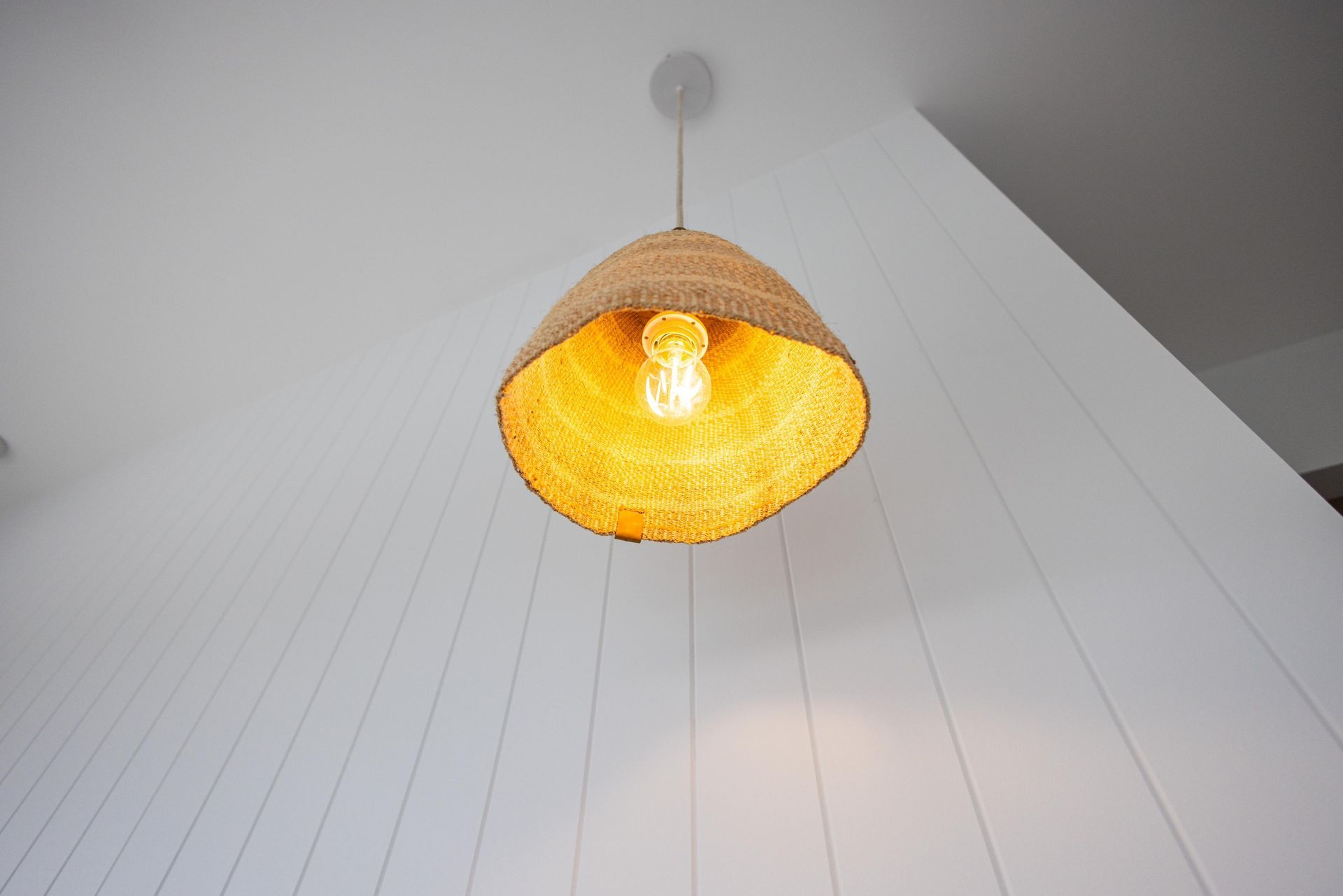 A wicker lamp hanging from the ceiling with a light inside
