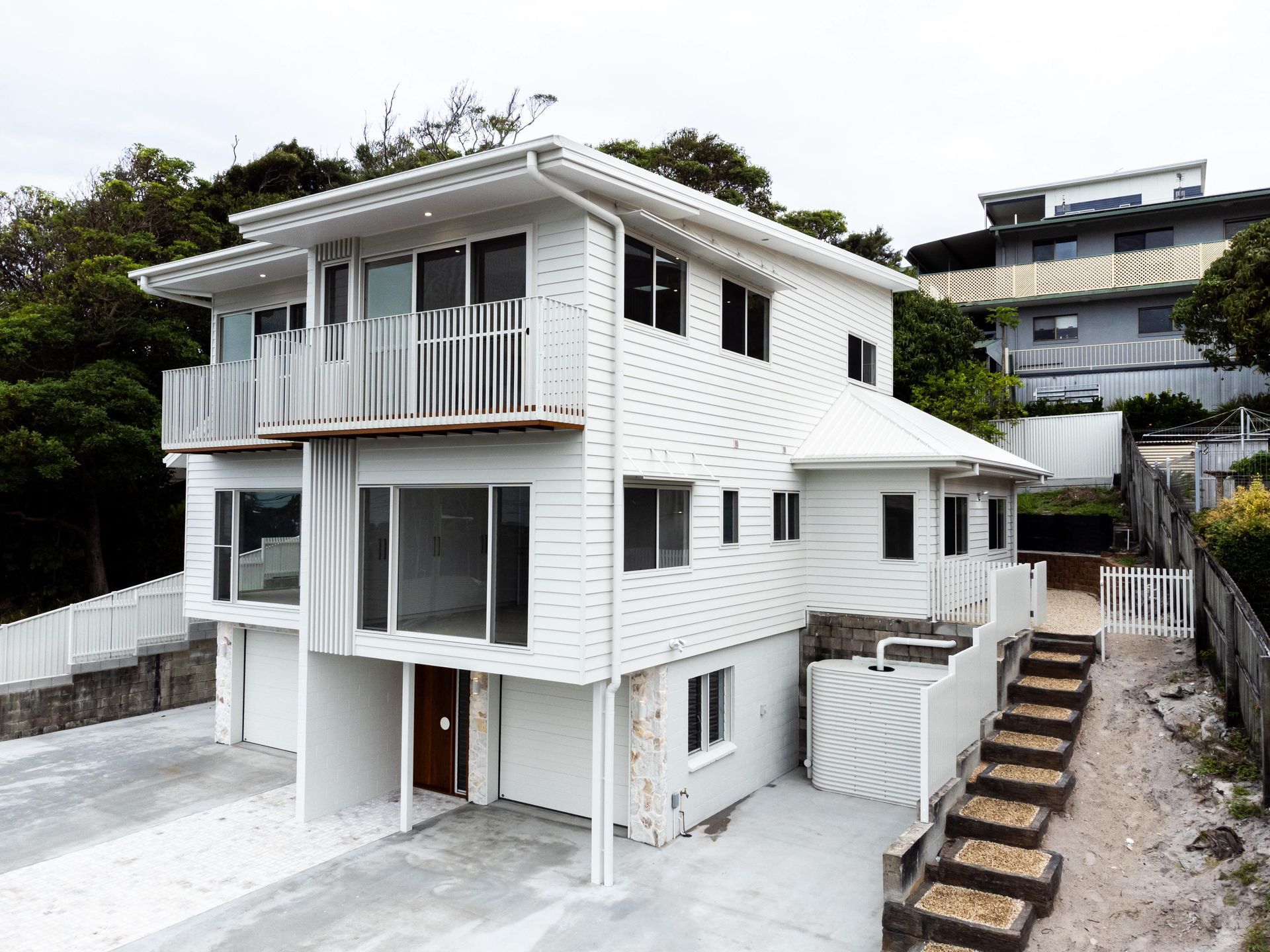 A large white house with stairs leading up to it is sitting on top of a hill.