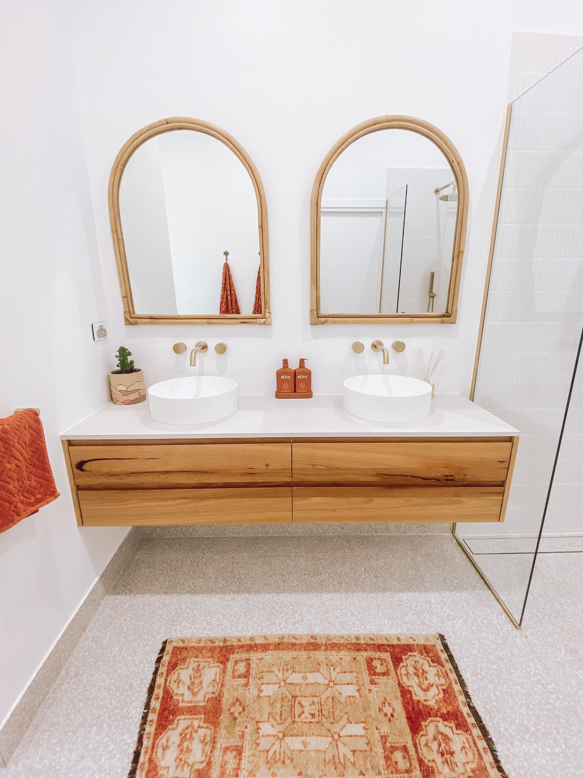 A bathroom with two sinks , two mirrors and a rug.