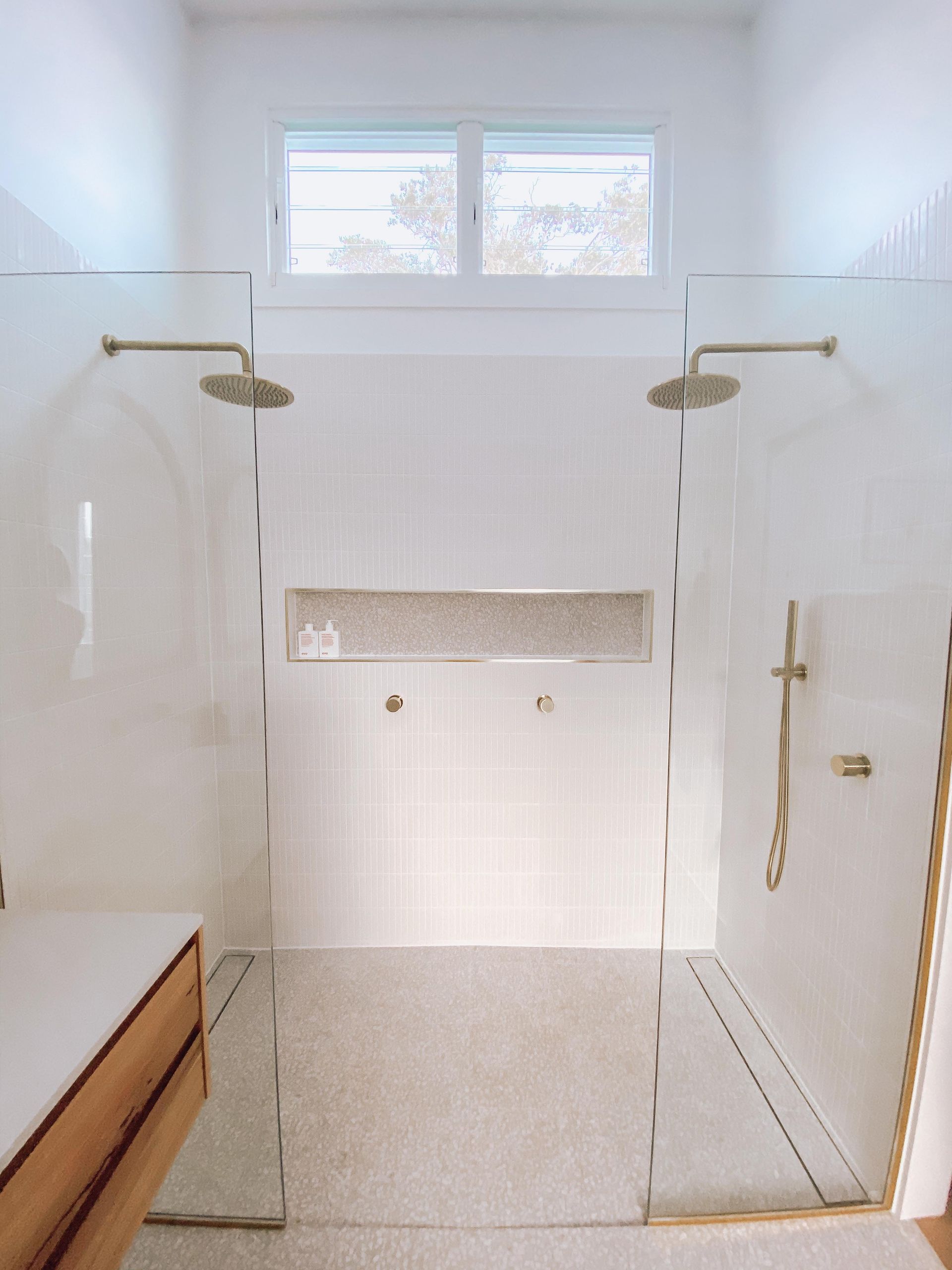 A bathroom with a walk in shower and two shower heads