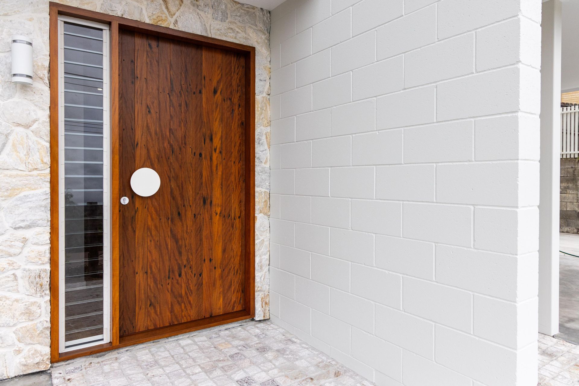 A wooden door is sitting in front of a white brick wall.