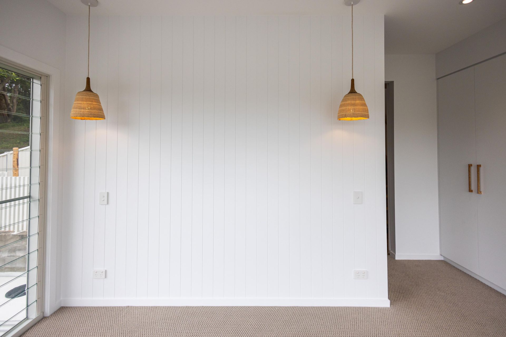An empty room with two pendant lights hanging from the ceiling.