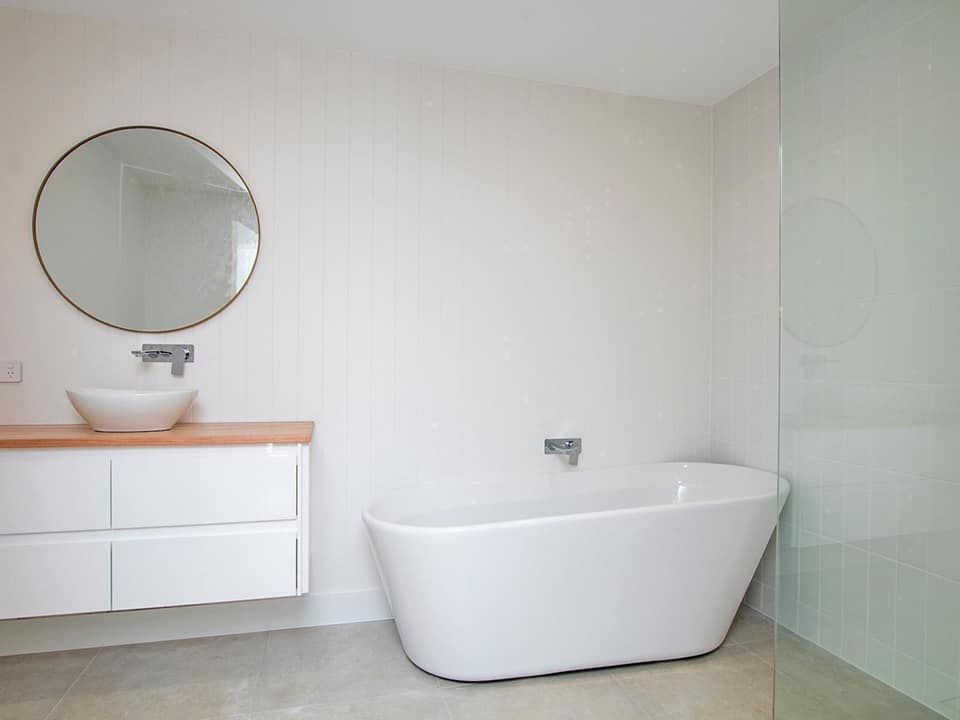 A bathroom with a bathtub , sink and mirror