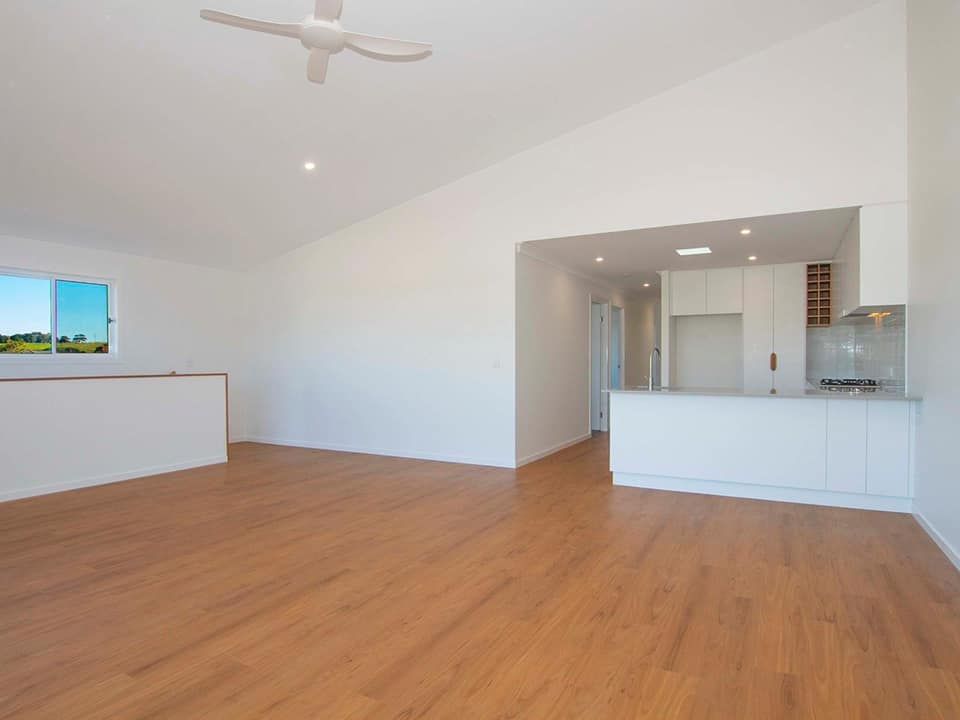 An empty living room with hardwood floors and a ceiling fan