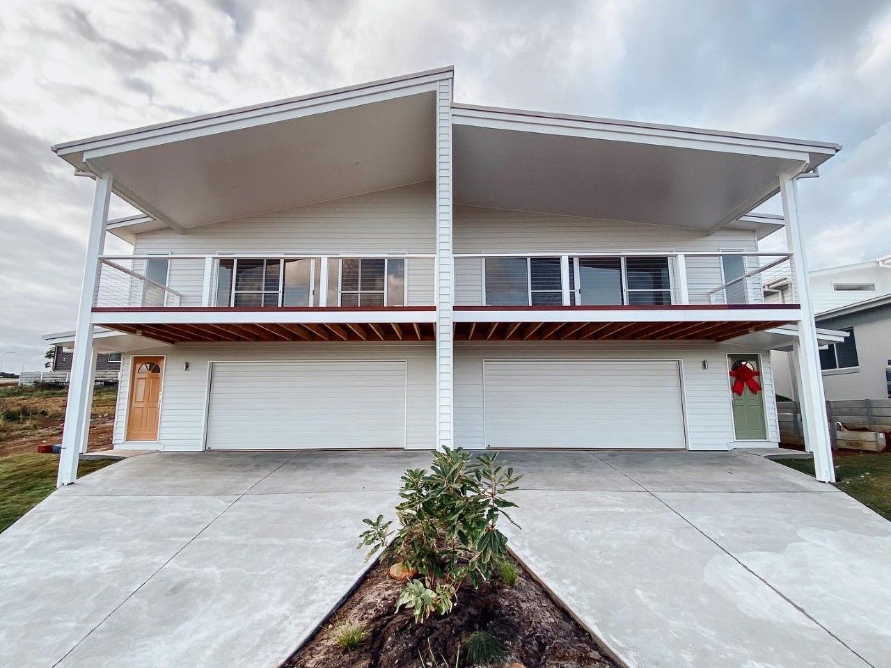 A large white house with two garages and a balcony.