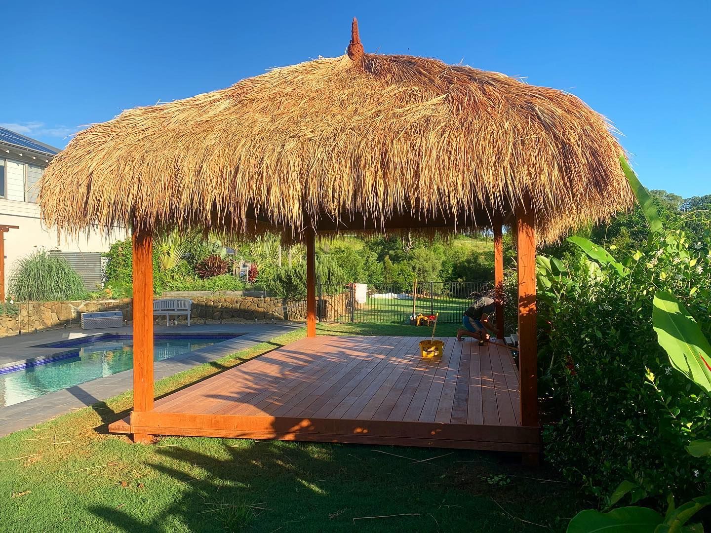 A gazebo with a thatched roof is sitting next to a pool.