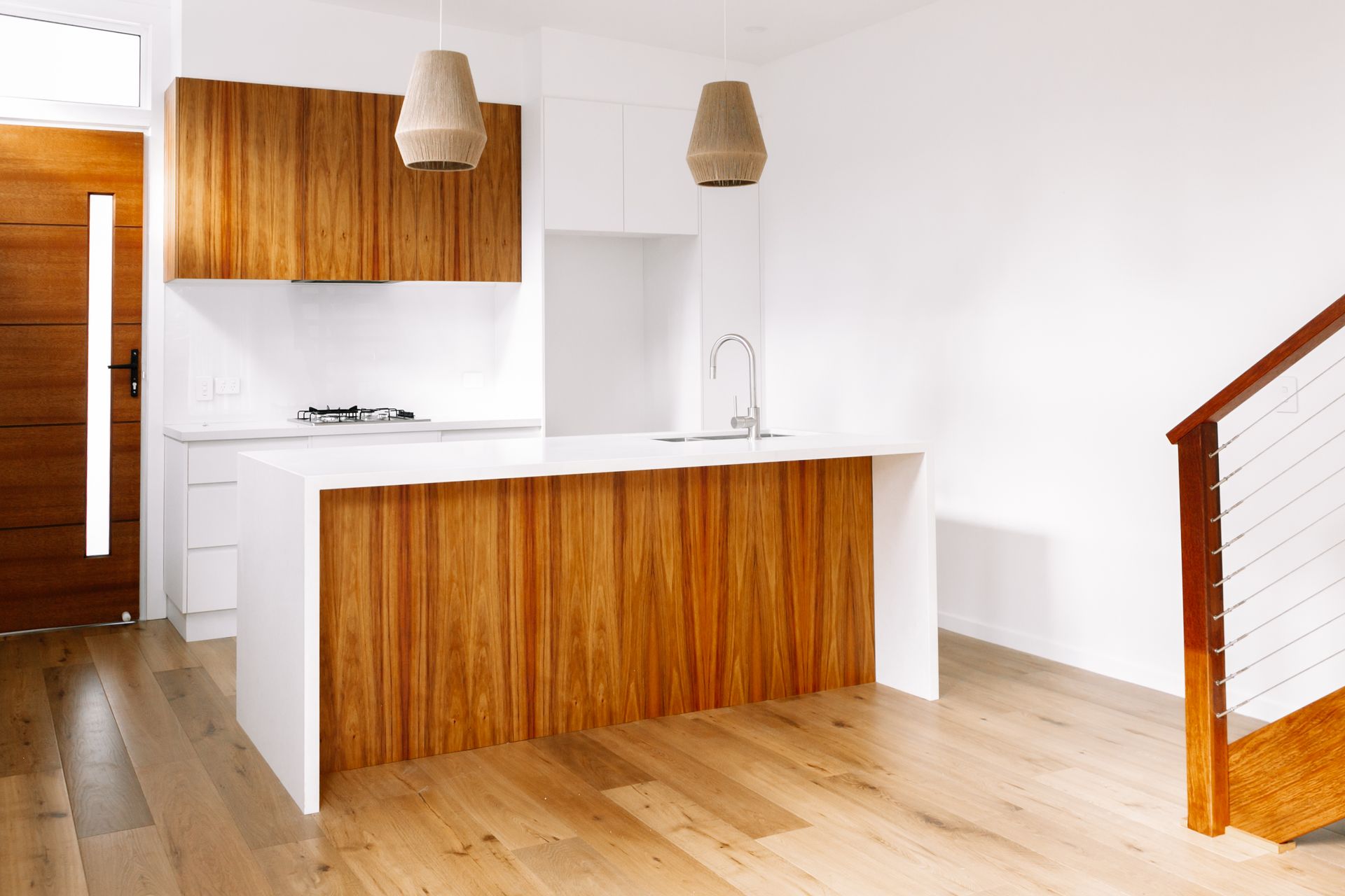 an empty kitchen with a wooden island and stairs .