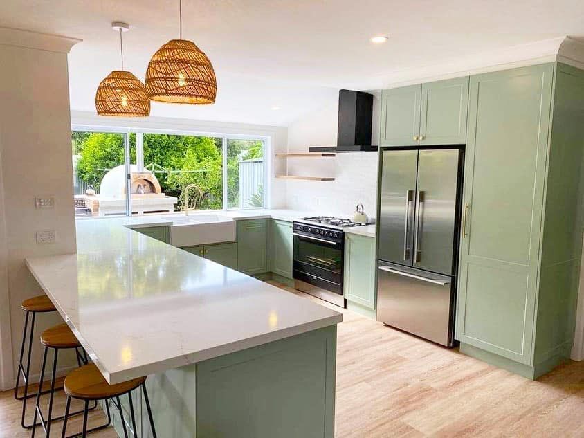 A kitchen with green cabinets and stainless steel appliances.