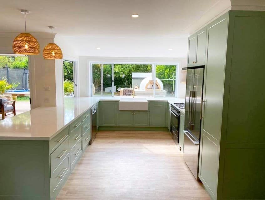 a kitchen with green cabinets and stainless steel appliances .