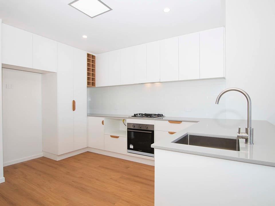 An empty kitchen with white cabinets and a sink