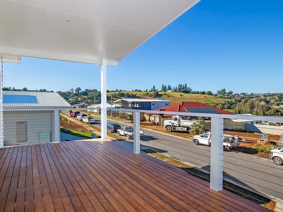 a wooden deck with a white railing and a view of a street .