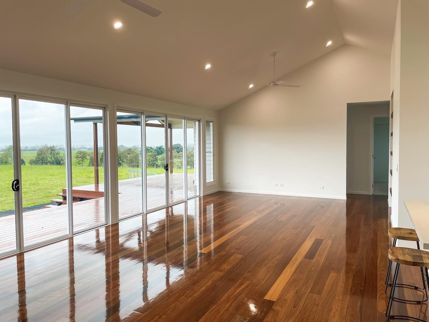 A large empty room with hardwood floors and lots of windows.